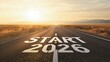 © MOON - START 2026 message painted on an endless desert highway during a dramatic golden sunset, representing the future, new resolutions, goals, and the beginning of a journey.