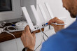© ronstik - Wireless internet. Service technician connecting ethernet cable to Wi-Fi router at home