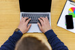 © Juan Algar - Hands typing on a laptop in a coworking space with documents and a smartphone nearby