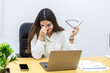 © Juan Algar - Woman sitting at desk in coworking space, stressed while using laptop