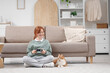 © Pixel-Shot - Redhead teenage girl with cute cat playing video game at home
