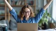 © morepiixel - A woman joyfully celebrates in front of her laptop, expressing excitement and achievement in a cozy home setting.