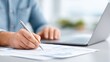© Дмитрий Баронин - Accountant working diligently at a desk, writing notes on financial documents, with a laptop open, showcasing a professional workspace and focus on financial management