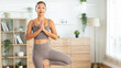© Leny Studio - Flexible Asian woman doing yoga pose with copy space, healthy lifestyle and body stretching workout at home, fitness training in bright living room, well-being and mental health concept in soft light.