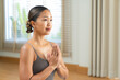 © Leny Studio - Flexible Asian woman doing yoga pose with copy space, healthy lifestyle and body stretching workout at home, fitness training in bright living room, well-being and mental health concept in soft light.