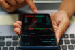 © Rifqi Muflih - Fingers Pointing At Stock Market Data On Smartphone Screen Displaying Candlestick Charts And Graphs