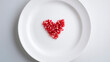 © Jess rodriguez - Red pomegranate seeds forming a heart in the center of a white ceramic plate, concept of cardiovascular health and healthy eating
