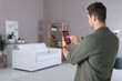 © New Africa - Smart home system. Man using app on mobile phone to control house features in room