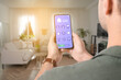 © New Africa - Smart home system. Man using app on mobile phone to control house features in room, closeup