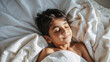 © Larysa - Peaceful young boy sleeping soundly in soft white bedding bathed in warm sunlight