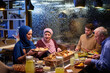 © .shock - Muslim family enjoying iftar meal in a restaurant with Ramadan decorations during evening hours