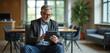 © Pete - Mature businessman with glasses uses tablet in modern office lounge. Sits in armchair looking at screen. Background shows meeting area with tables, chairs. Pro works on digital device inside
