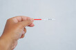 © Munif Rifa'i - A hand holds a pregnancy test strip showing two red lines, indicating a positive result. Set against a plain white background, symbolizing a life-changing moment