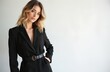© Maryna - Fashionable young woman with wavy blond hair wears black blazer cinched with belt. Poses confidently against light background, showing stylish attire, natural makeup. Hand in pocket.