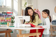 © Pixel-Shot - Happy Asian mother and her daughter working with sewing machine in workshop