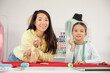 © Pixel-Shot - Happy Asian mother and her daughter with chalks in sewing studio