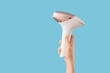 © Pixel-Shot - Female hand with photoepilator on blue background. Depilation concept