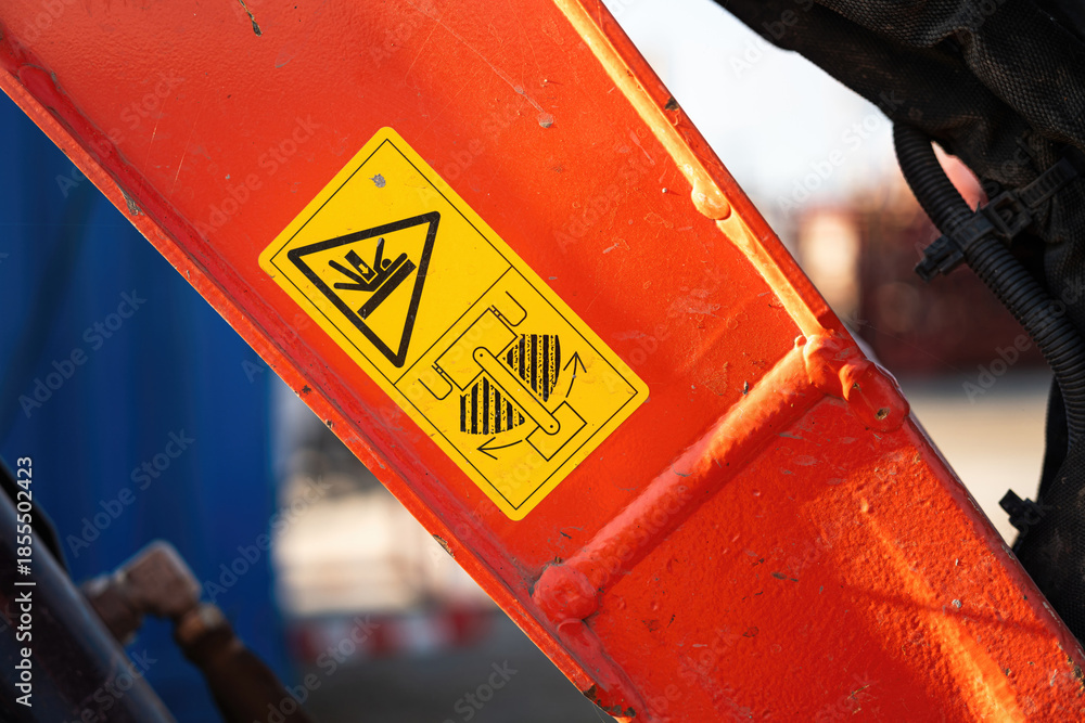 Safety caution sign on the backhoe front part, instruciton for keep out from the swing radius to prevent the accident. Safety sign on the industrial machine, close-up.