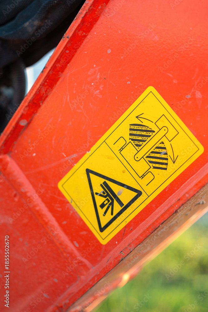 Safety caution sign on the backhoe front part, instruciton for keep out from the swing radius to prevent the accident. Safety sign on the industrial machine, close-up.