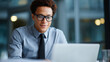 © valeo5 - Professional young businessman wearing stylish black glasses and formal attire focused on working on his laptop in a modern office environment with soft bokeh background lighting at daytime