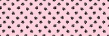 Seamless pattern of black cat or dog paw prints with heart shapes on a pastel pink background. Minimalist animal footprint wallpaper for pet-themed designs, textile, wrapping paper, and scrapbooking.
