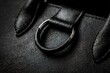 © Iftikhar alam - Close up view of a black purse showcasing its textured surface and metal ring detail on the handle, emphasizing its design and craftsmanship in a well-lit setting