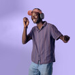 © Lomb - Young Black man dancing and enjoying music with wireless headphones in studio