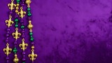 Mardi gras beads and fleur de lis on purple background