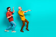 © deagreez - Two friends enjoy playful dance pose on teal background showcasing friendship energy and casual style