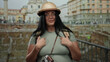 © Krakenimages.com - Woman tourist in front of ancient roman ruins surprised by surroundings in rome city wearing helmet and backpack posing curiously with lush background buildings.