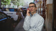 © Krakenimages.com - Caucasian man smiling while talking on smartphone outdoors on a busy street, surrounded by blurred cars and people, wearing glasses, conveying a sense of connectivity and urban life.