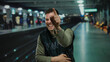 © Krakenimages.com - Young man smiling in a train station, showcasing a casual and friendly demeanor, with blurred lights in the background indicating movement and urban environment