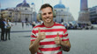 © Krakenimages.com - Young man with headphones giving thumbs up in urban setting of st. peter's square, showcasing a casual and happy vibe with a scenic background in rome's vibrant atmosphere.