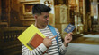 © Krakenimages.com - Young man holding a united states passport and pointing at it inside a church setting with books, showcasing travel and education themes.