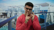 © Krakenimages.com - Young man in glasses smiling on a cruise ship while talking on a smartphone, enjoying the outdoor ocean view and relaxed atmosphere.