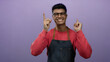 © Krakenimages.com - Young hispanic man in glasses and apron points upward smiling against a solid purple background, wearing a red sweater, expressing joy and positivity in a studio portrait.