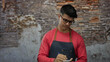 © Krakenimages.com - Young hispanic man in glasses and apron writing notes in a city street setting, focusing intently as he interacts with the urban environment.