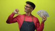 © Krakenimages.com - Man holding american dollars smiling against an isolated yellow background wearing glasses and a red shirt showcasing financial success and confidence.