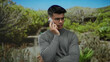 © Krakenimages.com - Handsome man in glasses talking on phone outdoors in a park setting surrounded by lush greenery showcasing a serene connection with nature and modern communication.