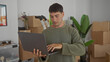 © Krakenimages.com - Man holds laptop and types on keyboard in building filled with moving boxes and houseplants; productivity focus.