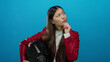 © Krakenimages.com - Woman in red jacket pondering holding helmet against blue background with thoughtful expression implying decision-making setting.