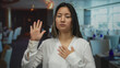 © Krakenimages.com - Chinese woman making oath gesture in an indoor restaurant setting with a focused expression, capturing a moment of sincerity and solemnity against a modern backdrop.