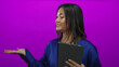 © Krakenimages.com - Chinese woman holding tablet in front of pink wall demonstrating gesture with her hand, wearing blue blouse, smiling, youthful expression, isolated against vibrant backdrop.