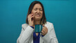 © Krakenimages.com - Young chinese woman holds coffee cup over blue background with a painful toothache expression, capturing a relatable moment of discomfort.
