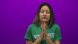 © Krakenimages.com - Woman volunteer shivering in cold wearing green t-shirt against vibrant purple background portraying discomfort and chill.