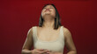 © Krakenimages.com - Young woman breathing deeply against a bold red wall conveying calmness with serene expression and isolated background emphasizing tranquility and peaceful contemplation