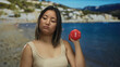© Krakenimages.com - Woman lifting dumbbell by the seaside with a focused expression, showcasing strength and determination in an outdoor beach setting under clear skies.