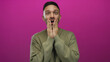 © Krakenimages.com - Young hispanic man with surprised expression stands against a vibrant pink background, hands on face in disbelief, showcasing emotional reaction and contemporary fashion.
