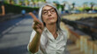© Krakenimages.com - Senior woman with grey hair gesturing no with fingers while standing outdoors on a street in a casual setting showcasing body language and emotion.
