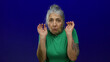 © Krakenimages.com - Senior woman with grey hair and tattoos expressing uncertainty on an isolated blue background.